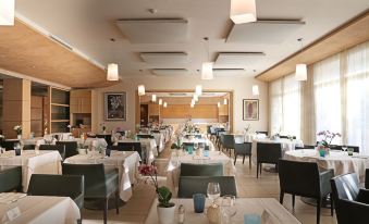 a large , well - lit dining room with tables and chairs arranged for a group of people at Hotel Caesius Thermae & Spa Resort