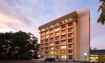 a tall building with a parking lot in front of it , surrounded by trees and cars at Frontier Hotel Darwin