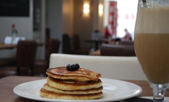 a stack of pancakes with blueberries on top and a cup of coffee in the background at Limes Apartments