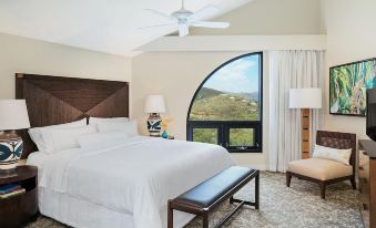 a hotel room with a king - sized bed , a desk , and a window overlooking a beautiful mountain view at The Westin St. John Resort Villas