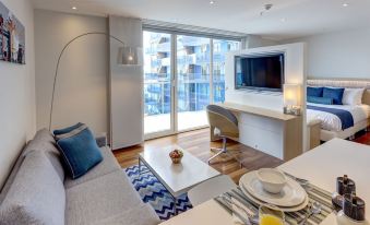 a modern living room with a white couch , dining table , and a flat screen tv at Cosmos Pacifico Hotel