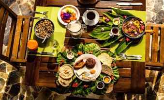 a wooden dining table with a variety of food items , including sandwiches , pancakes , and other dishes at Macaw Lodge