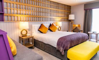 a large bed with yellow and purple pillows is in a room with a wooden headboard and lamps at Hotel Doolin