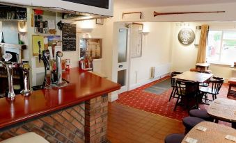 a small restaurant with a bar and dining area , featuring a red brick counter and chairs at The Trout Inn