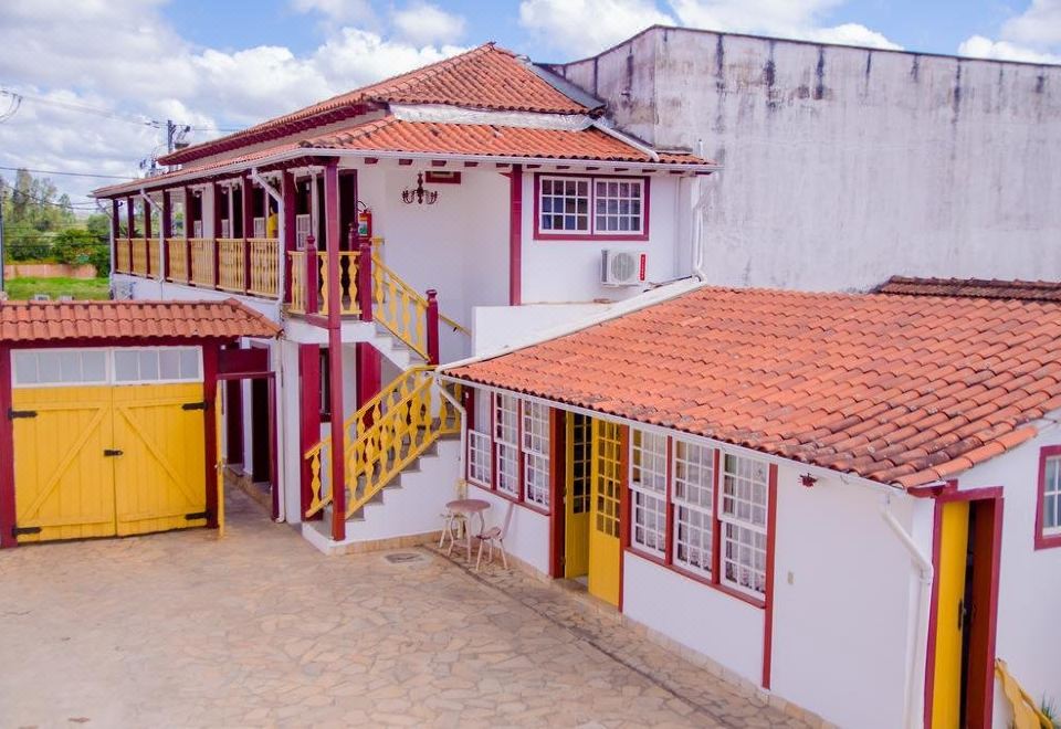 a red and white building with a balcony , surrounded by other buildings and a parking lot at Pousada Tesouro de MInas