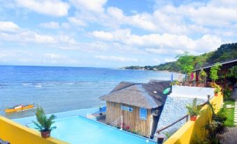 a tropical beach scene with a yellow house , blue swimming pool , and clear blue water at The Beachhouse