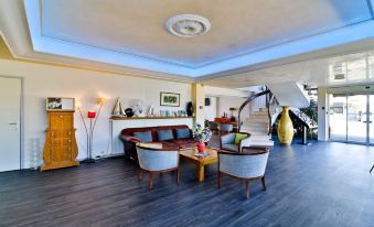 a modern living room with wooden flooring , white walls , and black coffee table , featuring comfortable seating arrangements and a spiral staircase at Hôtel Restaurant de la Mer