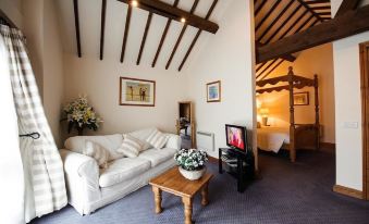 a cozy living room with a white couch , wooden coffee table , and a flat - screen tv at Church Farm Lodge