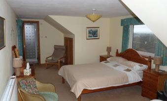 a spacious bedroom with a large bed , a chair , and a window overlooking the ocean at Ardwell Bed & Breakfast
