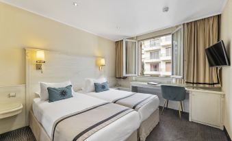 a modern hotel room with two beds , white bedding , and large windows , offering views of the city at Napoleon