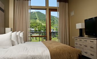a cozy bedroom with a large window overlooking a mountain range , creating a serene and tranquil atmosphere at Jay Peak Resort