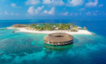 an aerial view of a tropical island with an overwater bungalow on stilts , surrounded by clear blue water at Kagi Maldives Resort & Spa