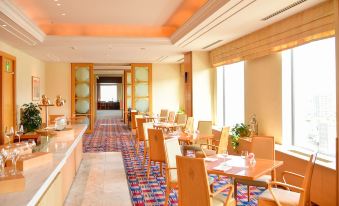 a modern dining room with wooden tables and chairs , a kitchen area , and large windows at Authent Hotel Otaru