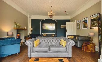 a living room with a gray couch , yellow and white pillows , a wooden floor , and a chandelier hanging from the ceiling at Crow How Country Guest House