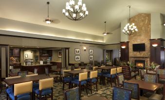 a dining area with multiple tables and chairs , as well as a fireplace in the background at Homewood Suites by Hilton Dover - Rockaway