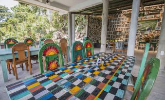 a colorful dining room with a long table covered in a checkered tablecloth , surrounded by chairs at Eco Hotel Uxlabil Atitlan