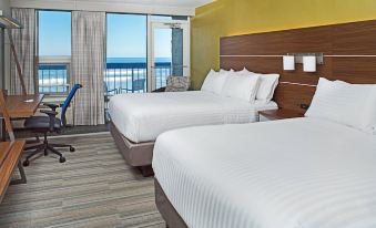 a hotel room with two beds , a chair , and a view of the ocean through large windows at Holiday Inn Express Nags Head Oceanfront