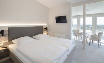a modern hotel room with a large bed , white walls , and a flat - screen tv on the wall at Hotel Bellevue