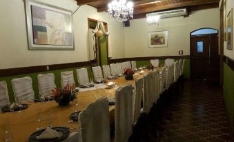 a long dining table is set with white chairs , wine glasses , and a centerpiece in a room with green walls at Hotel Astor