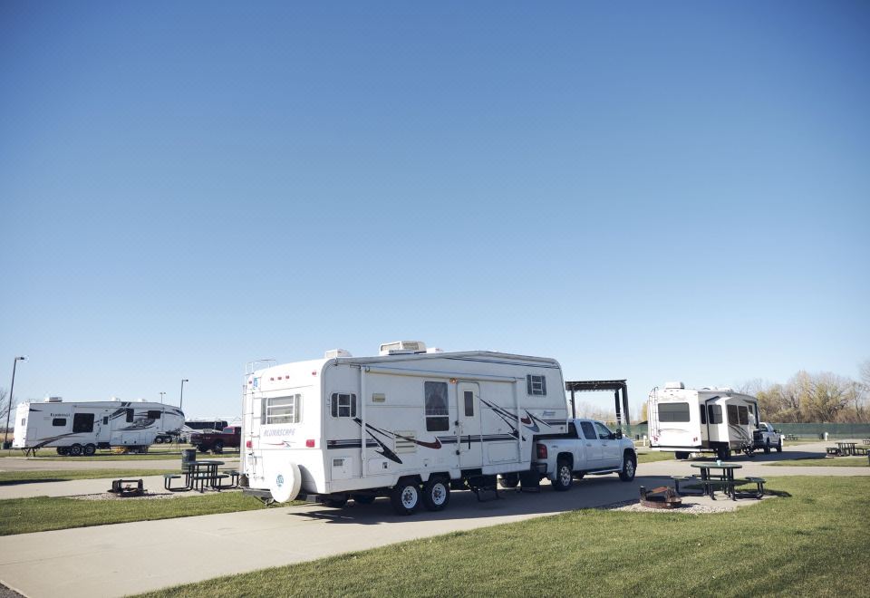 a white recreational vehicle ( rv ) parked in a grassy field , surrounded by other vehicles and vehicles at Jackpot Junction Casino Hotel