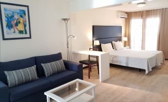 a living room with a couch , coffee table , and desk is shown next to a bedroom at Murdeira Village Resort