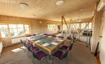 a large conference room with a wooden ceiling and walls , featuring a table surrounded by chairs and papers on it at Porto Resort