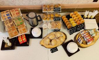 a dining table filled with a variety of pastries , including croissants , cakes , and donuts , as well as other desserts such as at The Lancaster Motel