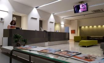 a modern hotel lobby with a reception desk , seating area , and posters on the wall at Hotel Artemide