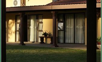 a house with a patio area , which has a table and chairs outside , and a view of the lawn and a gate at Mountain View Guest House