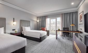 a modern hotel room with two beds , a desk , and a window offering a view of the city at Hyatt Hotel Canberra - A Park Hyatt Hotel