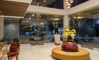 a lobby area with a large flower arrangement and several chairs in front of a large glass window at Horison Gkb Gresik
