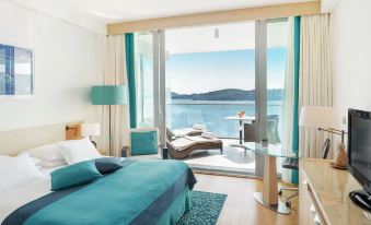a modern bedroom with a large window offering a view of the ocean , a bed , and a couch at Sun Gardens Dubrovnik