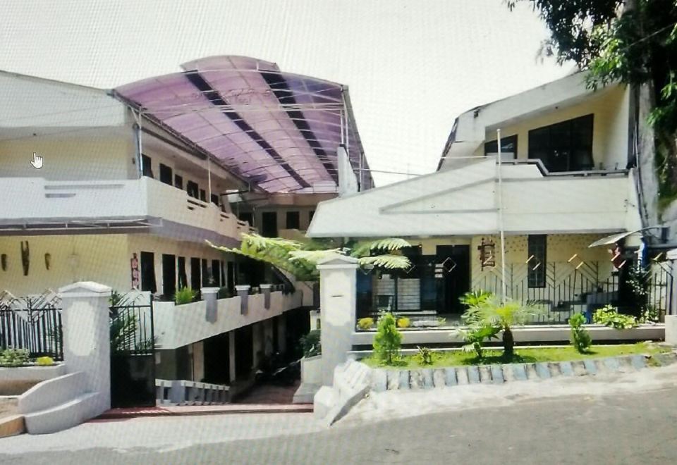 a modern building with a purple roof , surrounded by green plants and a clear blue sky at Adel Guest House