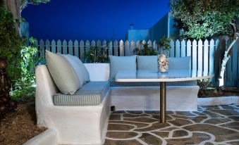 a white patio set with a table and chairs is set up in front of a fence at Hotel Iris