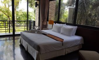 a large bed with white linens and a wooden headboard is situated in a room with a window at Suwan Golf and Country Club