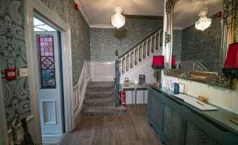 a foyer with a staircase leading to the second floor , adorned with red accents and decorations at Amarillo Guesthouse