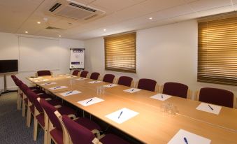 a conference room with a long table , chairs , and a projector screen , set up for a meeting or presentation at Premier Inn Sheffield City Centre (St Mary's Gate)