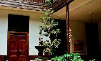 a courtyard with a fountain surrounded by potted plants and a wooden house with a balcony at Hotel Casablanca