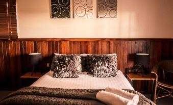 a bed with a wooden headboard and three paintings on the wall , creating a cozy atmosphere at Nannup Hideaway