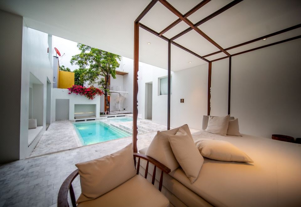 a modern , minimalist living space with a large bed and a swimming pool in the background at Sala Ayutthaya