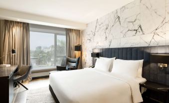 a large , white bed with a black headboard is in the center of a room with marble walls and a window at Radisson Blu Anchorage Hotel