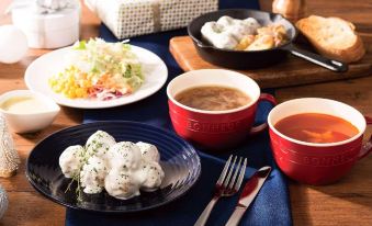 a dining table with a variety of food items , including bowls , plates , and utensils , as well as a cup of coffee at Comfort Hotel Koriyama