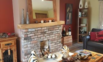 a cozy living room with a brick fireplace , a wooden coffee table , and a zebra print throw blanket at The Blue Bell Inn