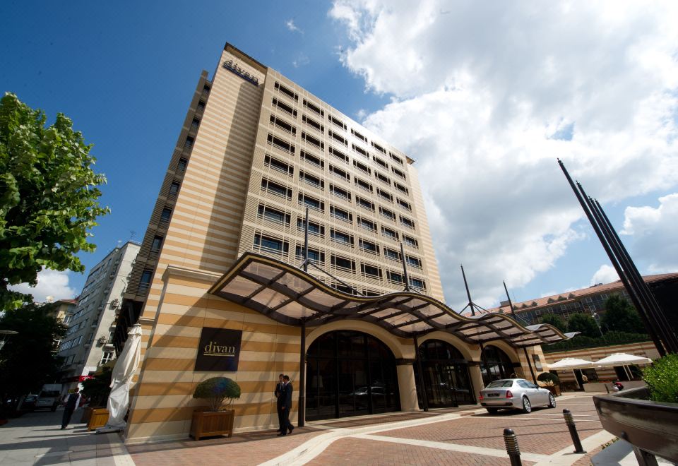 a large hotel building situated on a city street , with several cars parked in front of it at Divan Istanbul