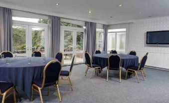 a large , empty room with multiple round tables and chairs set up for a meeting or event at Best Western Plus Oaklands Hotel