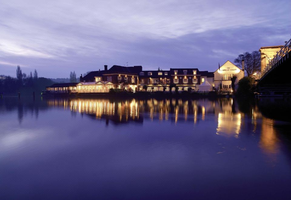 a large hotel is situated on the shore of a body of water at dusk at Macdonald Compleat Angler