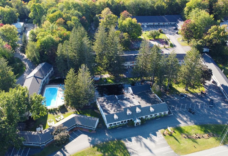 a bird 's eye view of a parking lot with buildings and trees surrounding a pool at Woodwards White Mountain Resort, BW Signature Collection