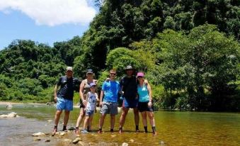 a group of five people , including two men and two women , are posing for a picture in a river at Mini Mansion