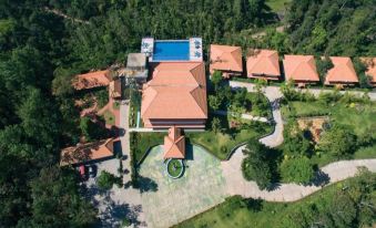 an aerial view of a large house surrounded by trees , with a swimming pool in the center at Coorg Cliffs Resort
