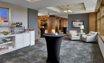 a modern bar area with a black table and chairs , surrounded by couches and other furniture at The Hotel Landing